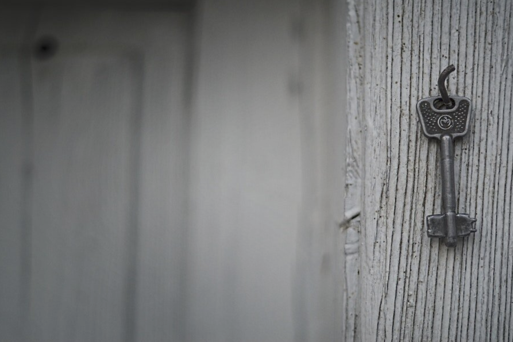 decorative image of gray, weathered wood with aan old fashioned key on a hook